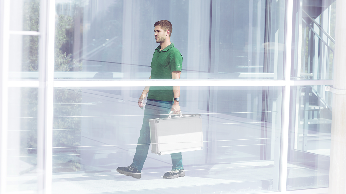 Person mit Koffer im modernen Gebäude Person geht mit einem Koffer durch ein Gebäude