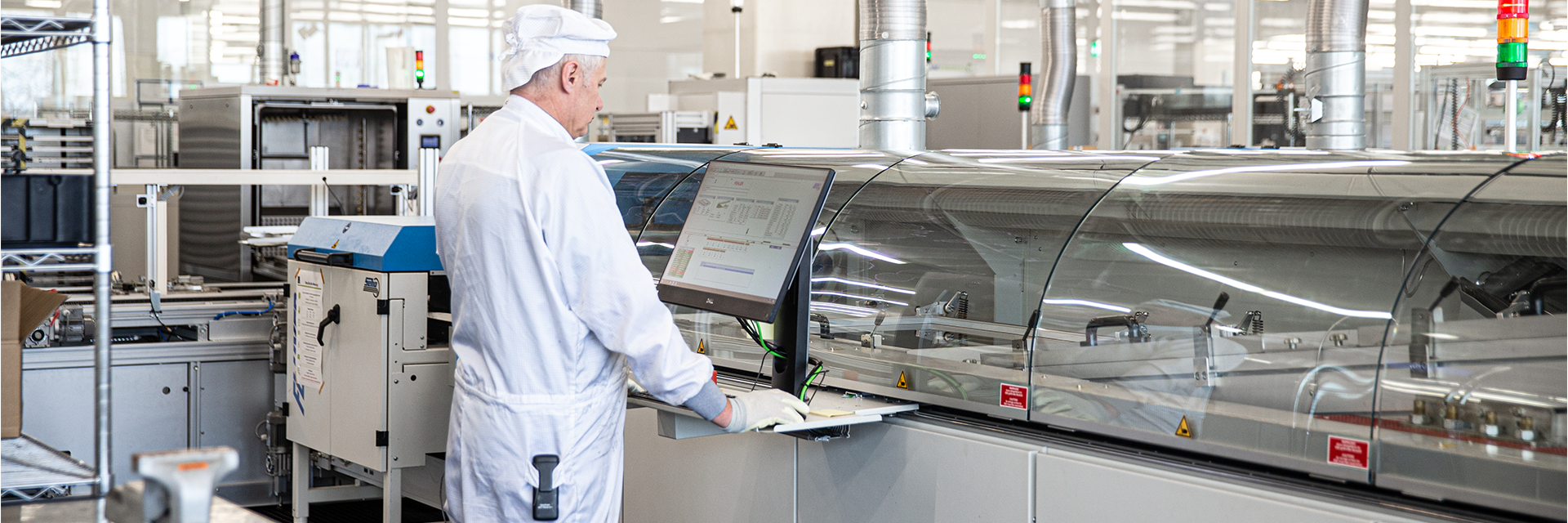 Arbeiten an Produktionsanlage Person bedient eine Produktionsanlage über ein Monitorpanel in einer Fertigungsumgebung