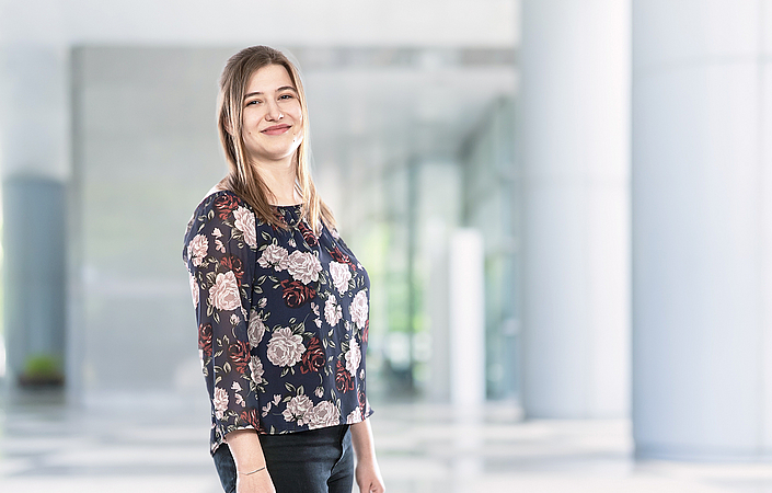 Jana im Masterstudium Person steht in einem modernen Gebäudebereich