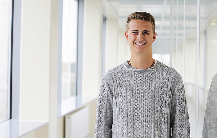 Thomas im Bachelorstudium Person steht in einem hellen Flur