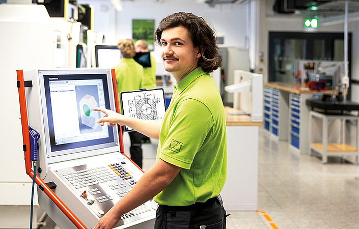 Einblick an der Maschinensteuerung Person bedient ein großes Maschinenbedienfeld in einer Werkstattumgebung
