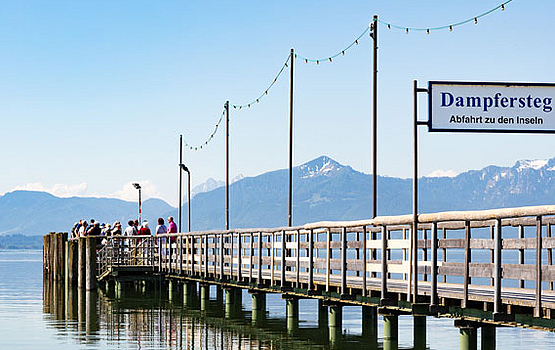 Steg am Wasser Langer Holzsteg mit Personen und Blick auf Wasser und Berge