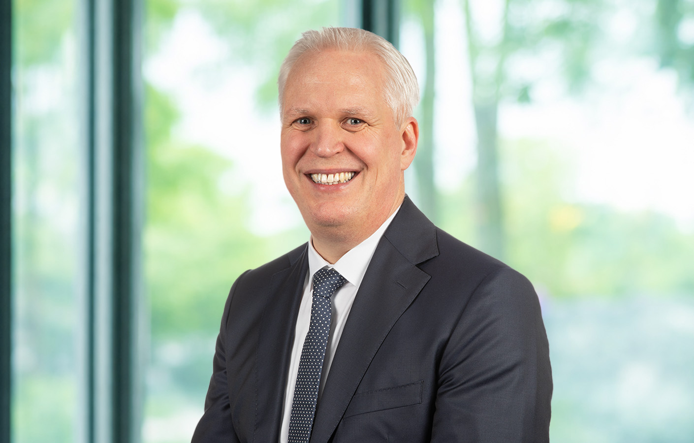 Dr. Peter Lücke Person in formeller Kleidung steht vor einer hellen Glasfassade